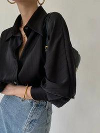 Elegante camisa con botonadura y detalles dorados de corte fluido